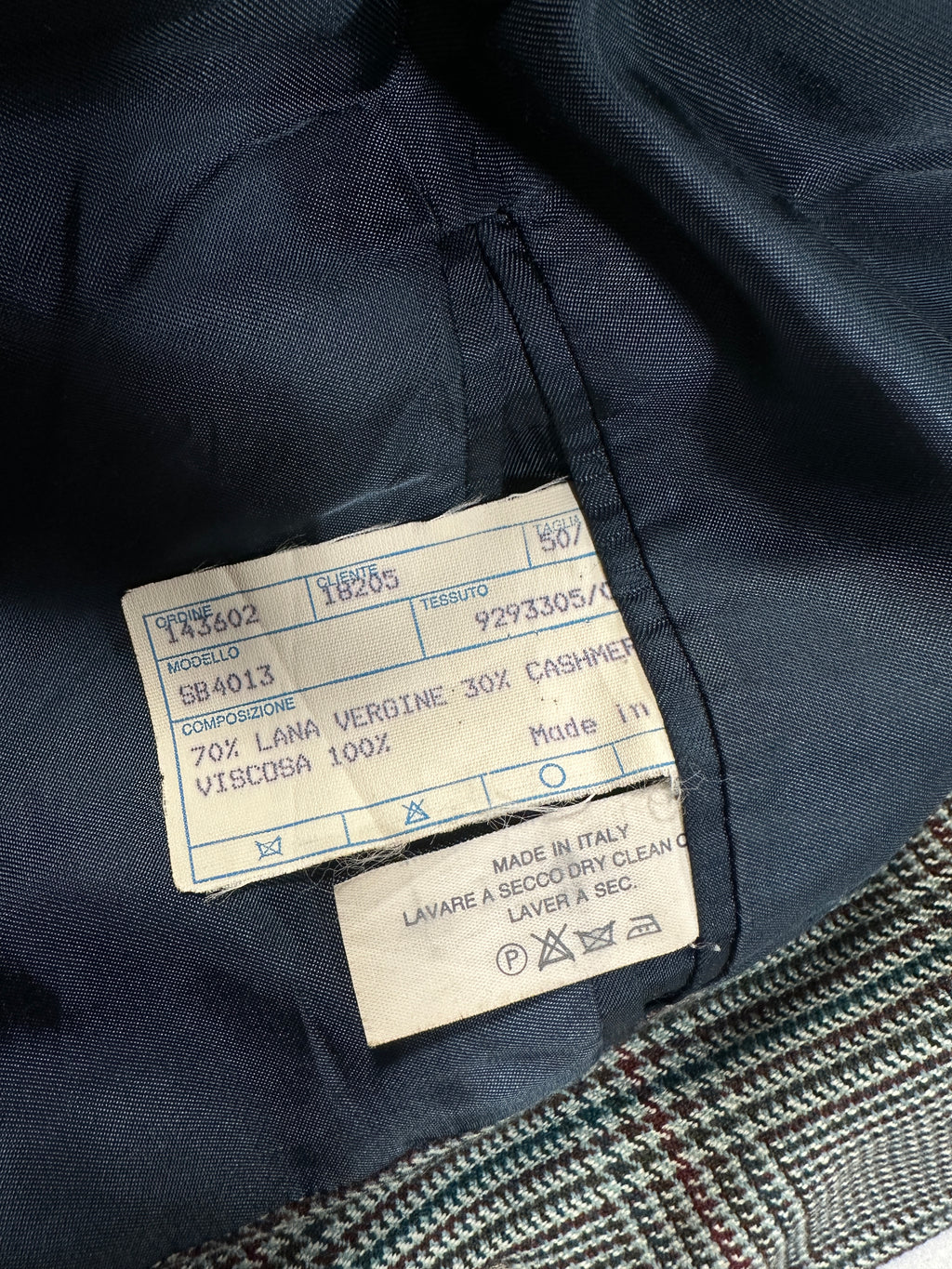 Close-up of a label on a dark fabric garment with visible text and numbers.